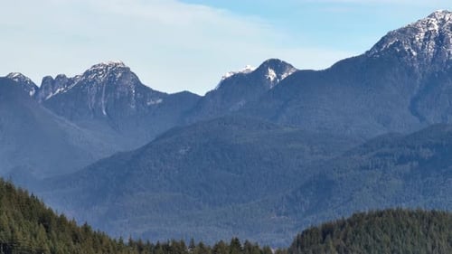 Evergreen Trees Frame Rugged Mountain Peaks Rising in the Distance on Burke Mountain in Canada -