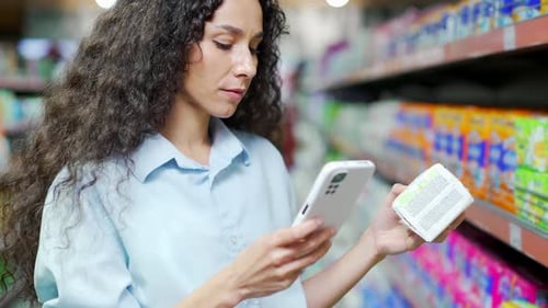 woman customer checking product information at mobile phone in supermarket Female Shopping In store