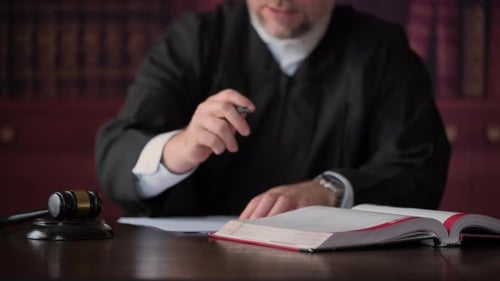 Male Judge Reviewing Case with Gavel in Courtroom