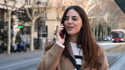 Pretty Happy Young Caucasian Woman Talking on the Phone in a City