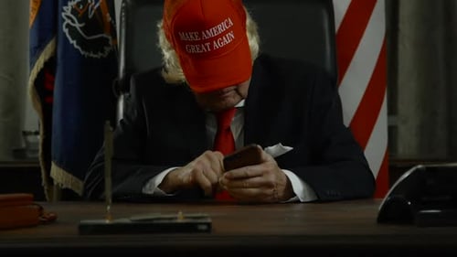 Trump sitting in oval office tweeting on his smart phone HD
