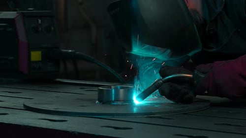 Man Welding Metal with Torch in Dark Workplace