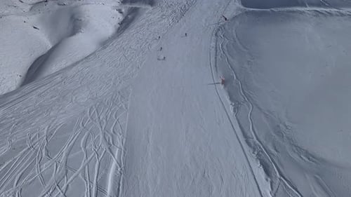 Skiers Descending Snowy Mountain Slope Aerial