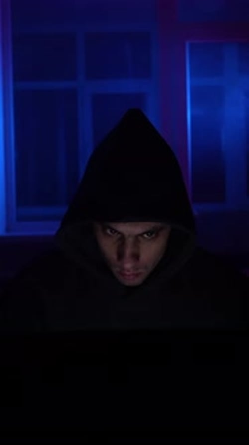 Person in Hooded Sweatshirt Looks Down Indoors at Night