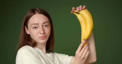 Girl with Ginger Hair Holding Bananas on the Plain Background