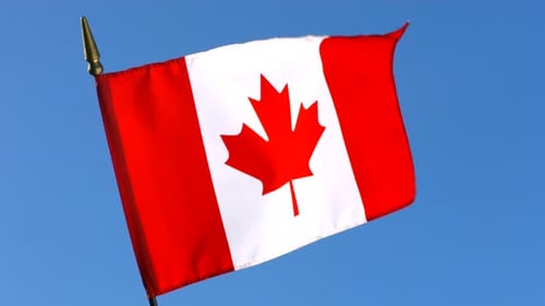 Canadian flag waving against clear blue sky background