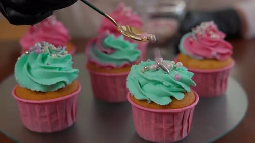 Closeup Edible Pearls Sprinkling on Cupcake with Green Rose Icing on Tray