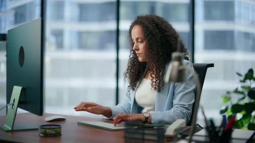 Thoughtful business woman typing keyboard in modern office workplace