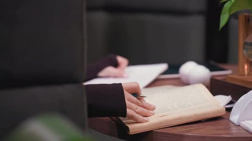Gros plan d'une femme tournant la page d'un vieux livre sur une table en bois