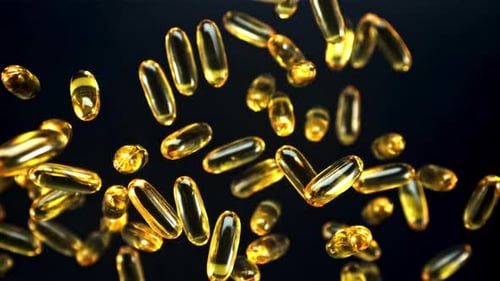 Golden Capsules Falling Against Black Background
