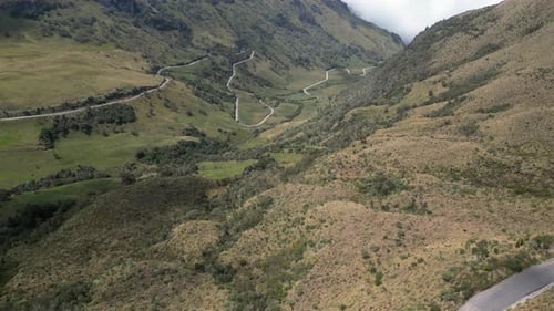 Pequena estrada sinuosa serpenteia por um vale estreito com curvas em ziguezague