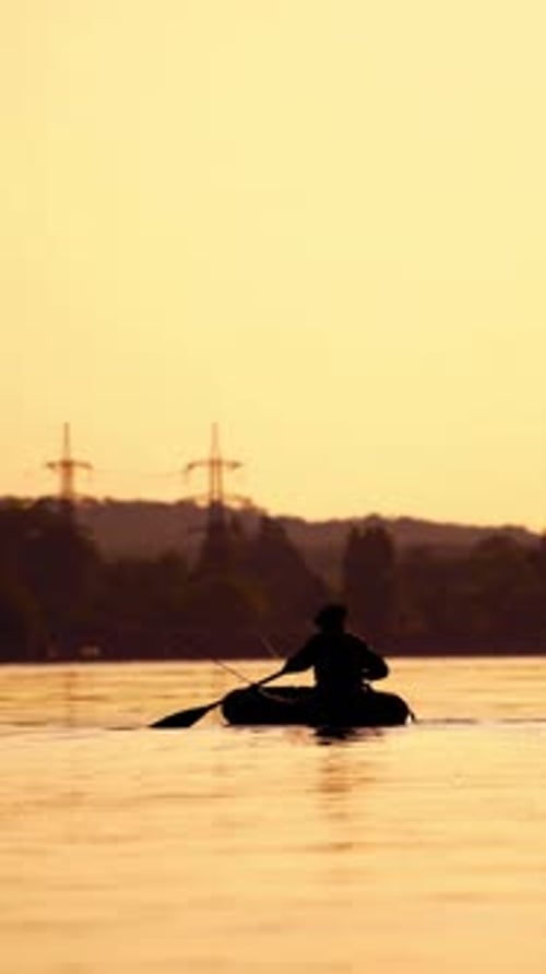 Mann fischt bei Sonnenuntergang von einem Boot aus.