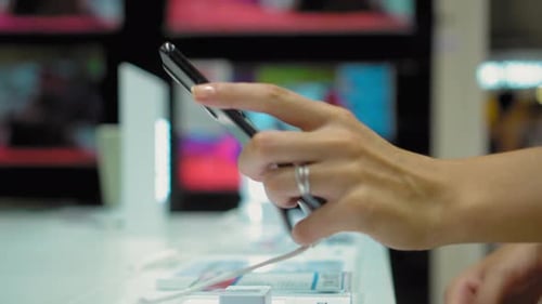 Women's hands take smartphone in store from counter and study, consider