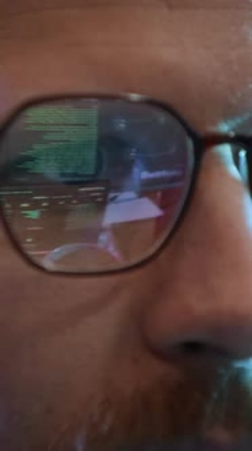 Ingeniero de redes con gafas que reflejan los códigos de programación en interiores