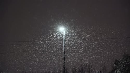 Heavy Snow Falling Under Streetlight at Night