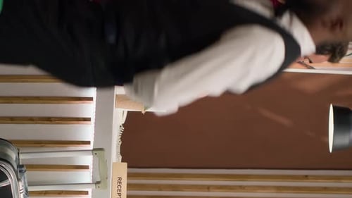 Woman Checking in Man at Hotel Reception Desk