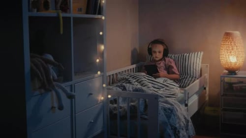Child using tablet in bed at night