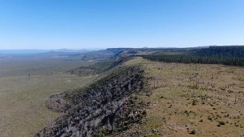 Drone shot capturing a hill from top perspective, devealing the wide landscape.