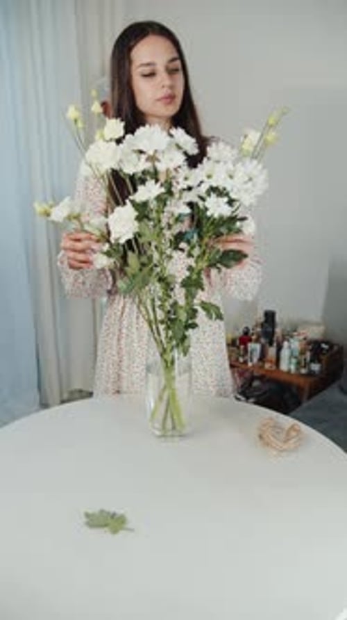 Woman Arranging Flowers in a Vase on Table