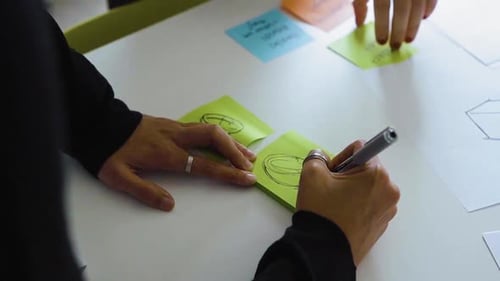 Unternehmens- professionelle Person zeichnet auf einem Haftnotiz ein Diagramm und eine Skizze eines Produkts für das Design.