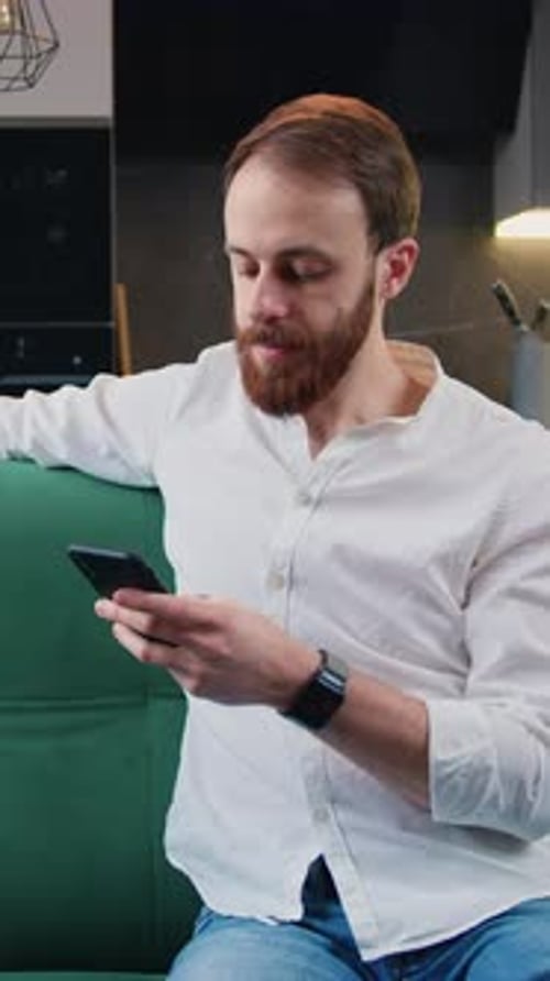 Man Relaxing on Sofa While Using Mobile Phone