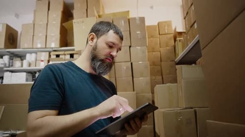Handsome Warehouse Worker Uses Digital Tablet for Checking Stock