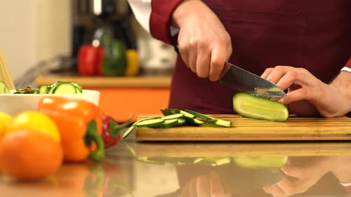 Male hands cut fresh cucumber.