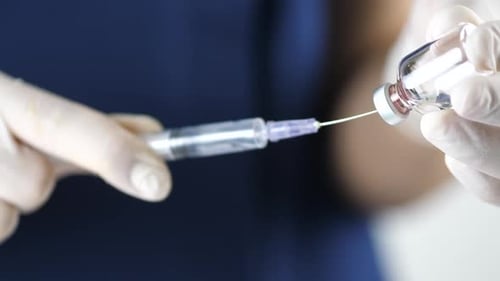 Medical Professional Draws Liquid from Vial with Syringe