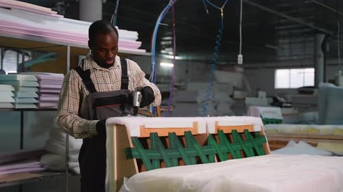Man Using Staple Gun in Furniture Factory