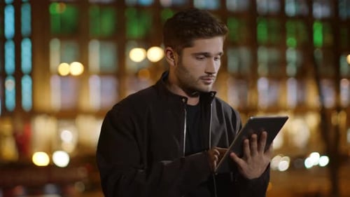 Portrait of Young Guy Surfing Internet on Tablet Computer Outdoors. Closeup Relaxed
