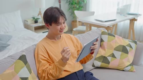 Young Adult Using Tablet at Home on Couch