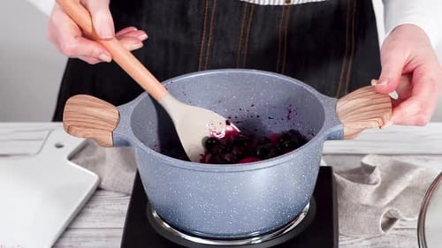 Cooking Berries in a Pan with a Spoon