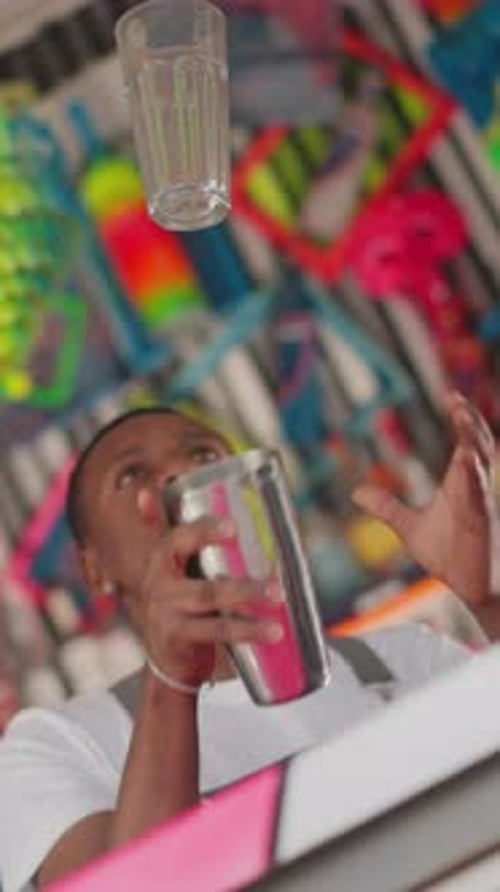 Barman with Shaker Tosses Glass in Bar