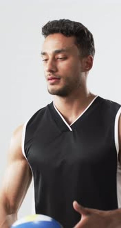 Young man tosses blue and yellow volleyball