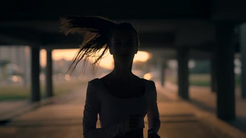 A Young Woman Runner is Training in the Summer Within a City