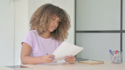 Woman Reviews Documents at Her Desk in Office