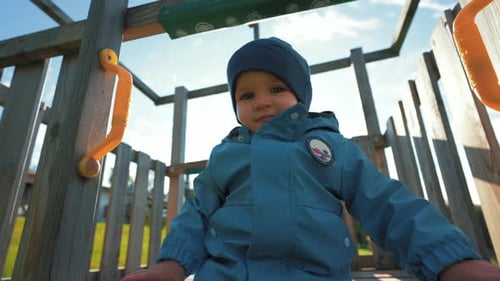 Cute Little Boy in Hat Prepares to Slide on Playground