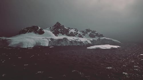 Dramatic Snowy Mountains and Icebergs in Dark Ocean