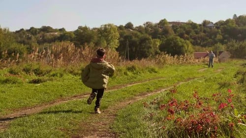 Child Runs to Man Flying Kite Outdoors