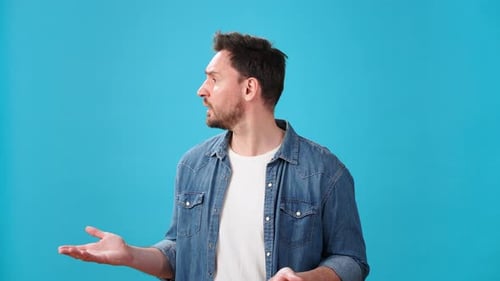 Young Man Looks Around in Confusion and Spreads Hands