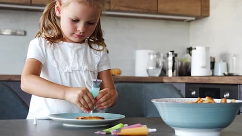 Little Girl Decorating Homemade Cookies with Glaze or Food Paints in Home Kitchen Family Hobby