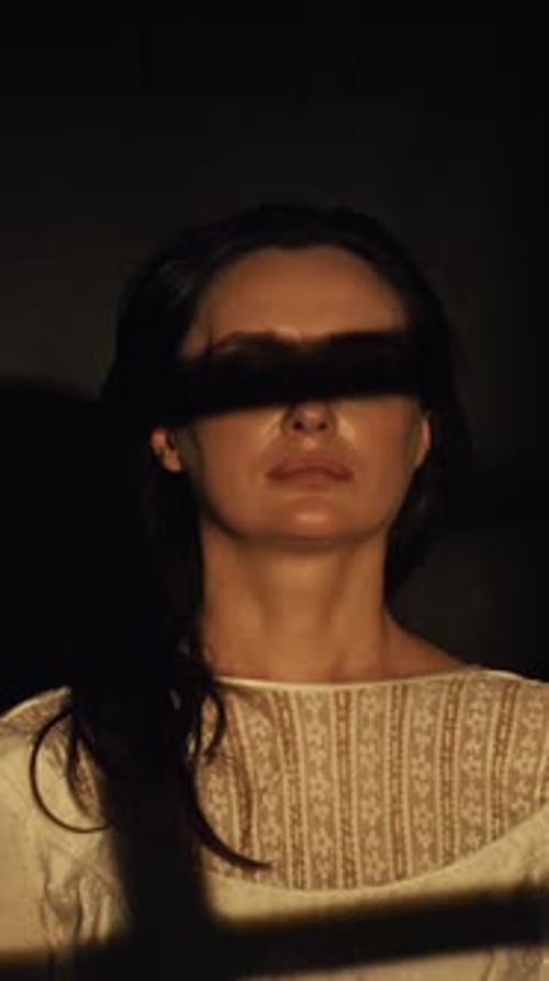 Close-up portrait of a woman with open stern eyes on a dark background