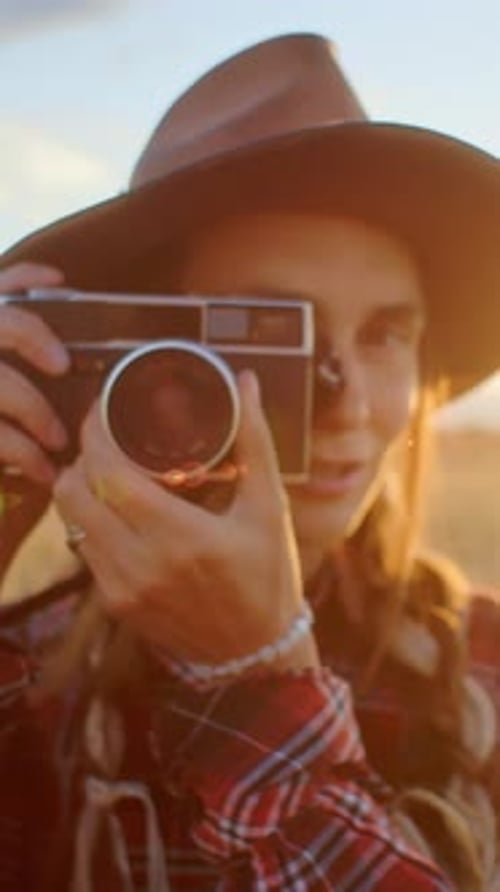 Photographer Taking Pictures with Vintage Camera in a Field at Sunset