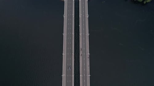 Aerial View of the Movement of Cars on a Double Bridge Over the River and a View of the City Among