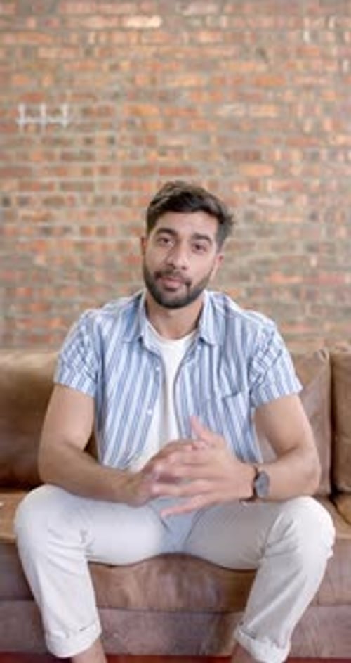 Man Explains Seated Indoors on Couch