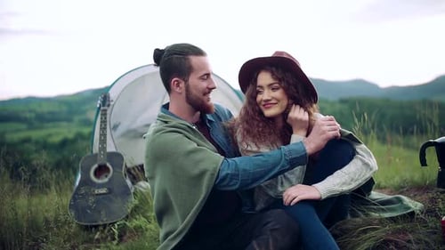Young couple resting in nature near tent shelter on summer holiday