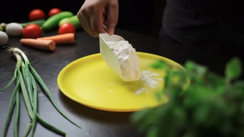 Spreading refined flour on a yellow coloured plate with scoop