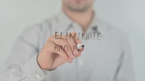 Writing 'Eliminate Bad Habits' on Clear Surface