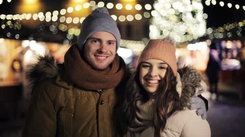 Love, Winter Holidays And People Concept - Happy Couple Hugging At Christmas Market In Evening