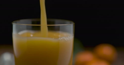 Fresh orange juice poured into clear glass indoors